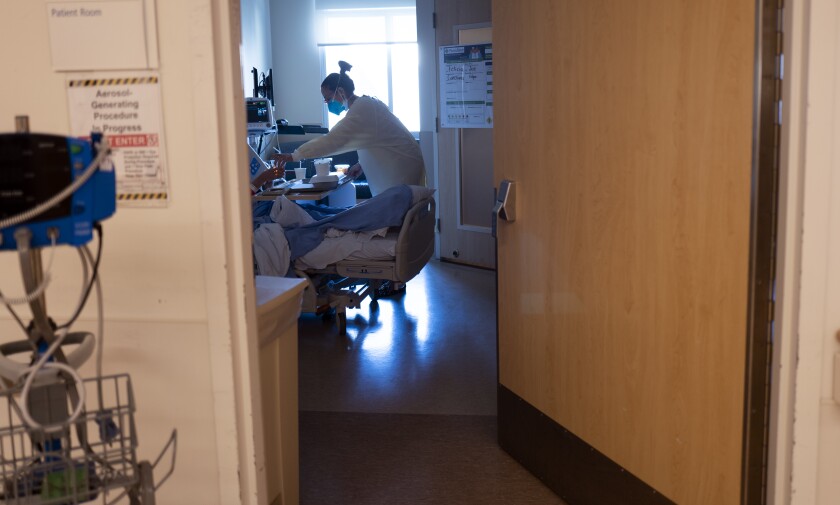 A physician hands some liquid to a hospitalized patient inside a COVID-19 unit.