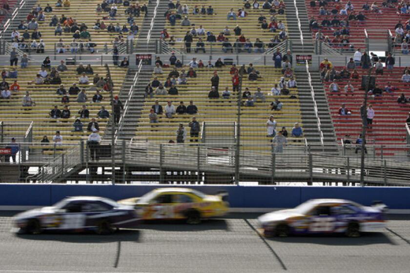 A sparse crowd watches a rain-delayed NASCAR Sprint Cup race at Auto Club Speedway in February 2008. Auto Club Speedway officials announced Friday they are reducing grandstand seating at the race track.