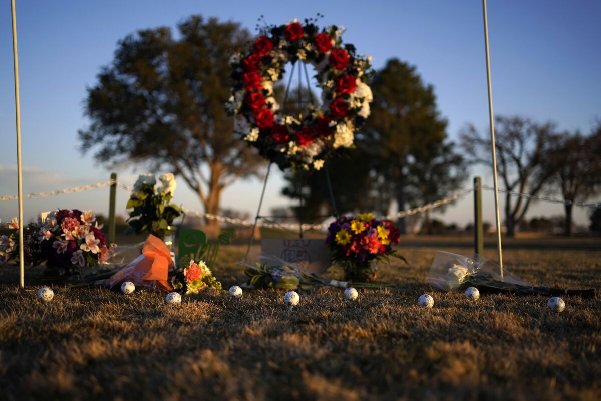 Memorial wreaths, bouquets and a line of golf balls on a golf course