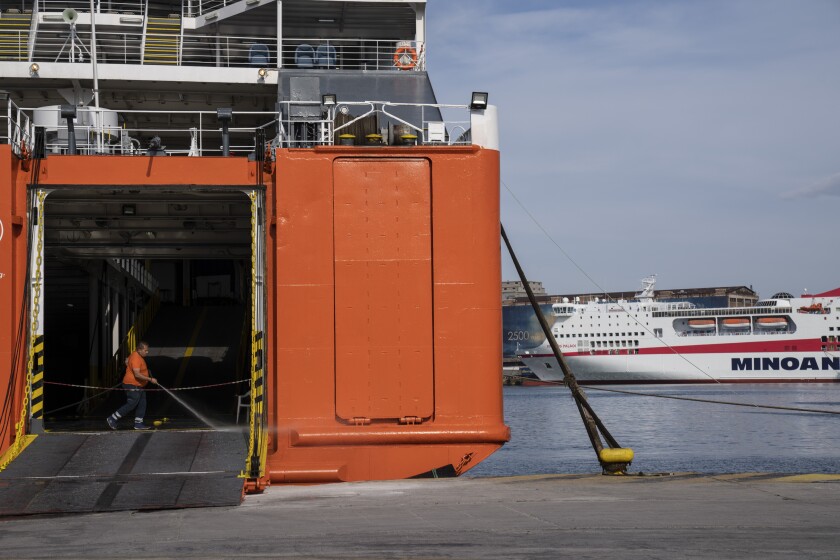 A seaman cleans the entrance of a docked ferry during a 24-hour labor strike at the port of Piraeus, near Athens, Wednesday, June 16, 2021. Greece's biggest labor unions staged a 24-hour strike to protest a labor bill being voted in parliament. (AP Photo/Petros Giannakouris)