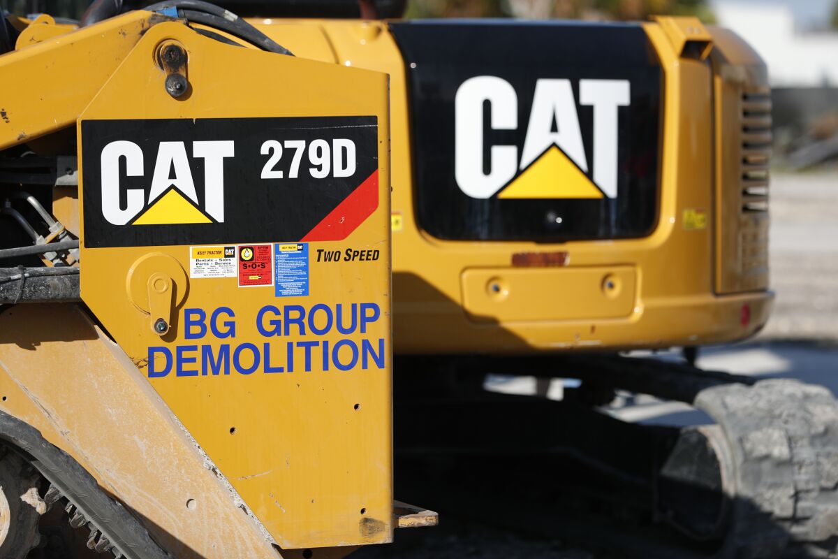 FILE - This May 8, 2019 photo shows a Caterpillar 279D Compact Track Loader, left, and 308E2 CR Mini Hydraulic Excavator, right, rear, at a demolition site in Fort Lauderdale, Fla. Construction equipment manufacturer Caterpillar says it's packing up its headquarters from its longtime home state of Illinois and heading to Texas. Caterpillar Inc. said Tuesday, June 14, 2022, that it's transferring its global base to Irving, Texas, from the Chicago suburb of Deerfield, Illinois. (AP Photo/Wilfredo Lee, File)