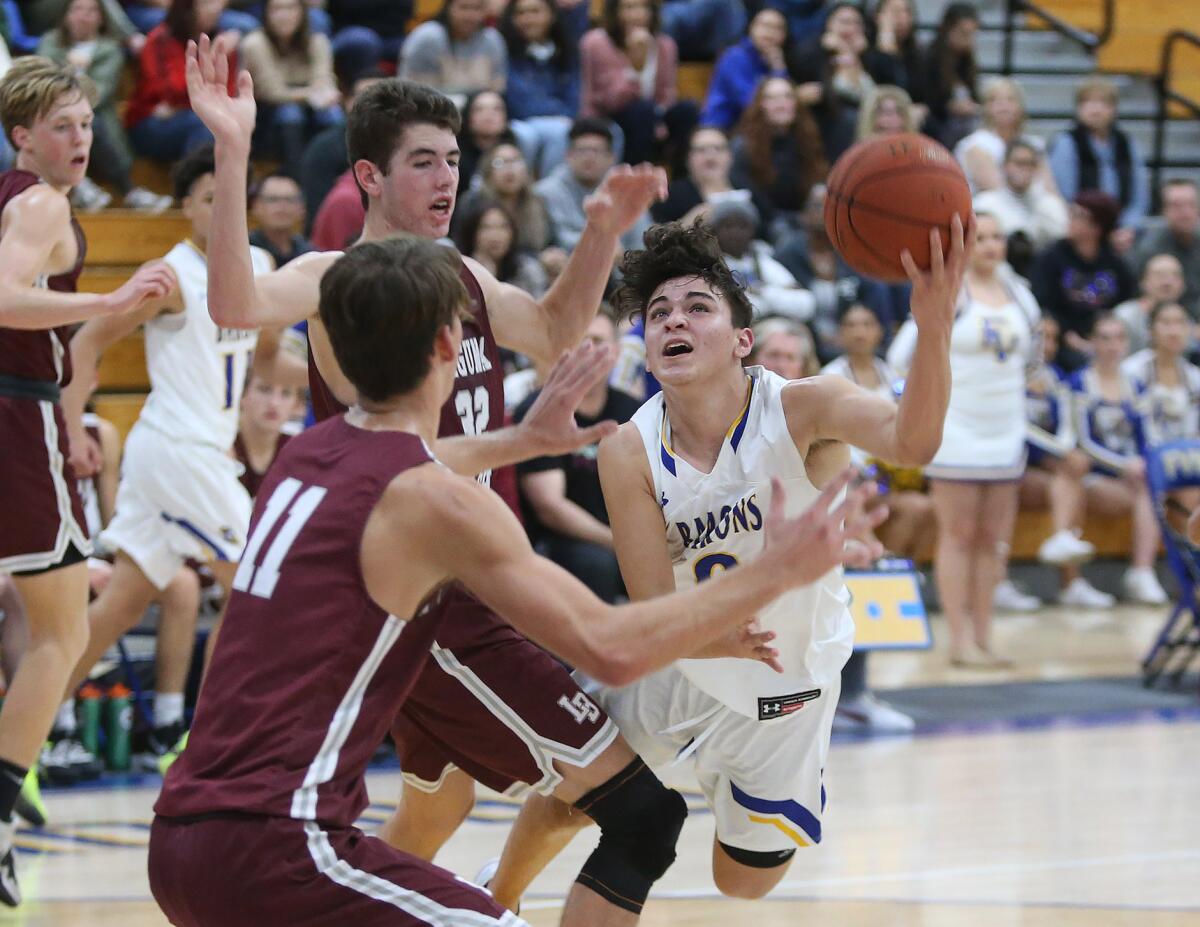 Fountain Valley's Preston Amarillo flips the ball in for a layup while being fouled by Laguna Beach's Nolan Naess (32) during a Wave League game on Wednesday.