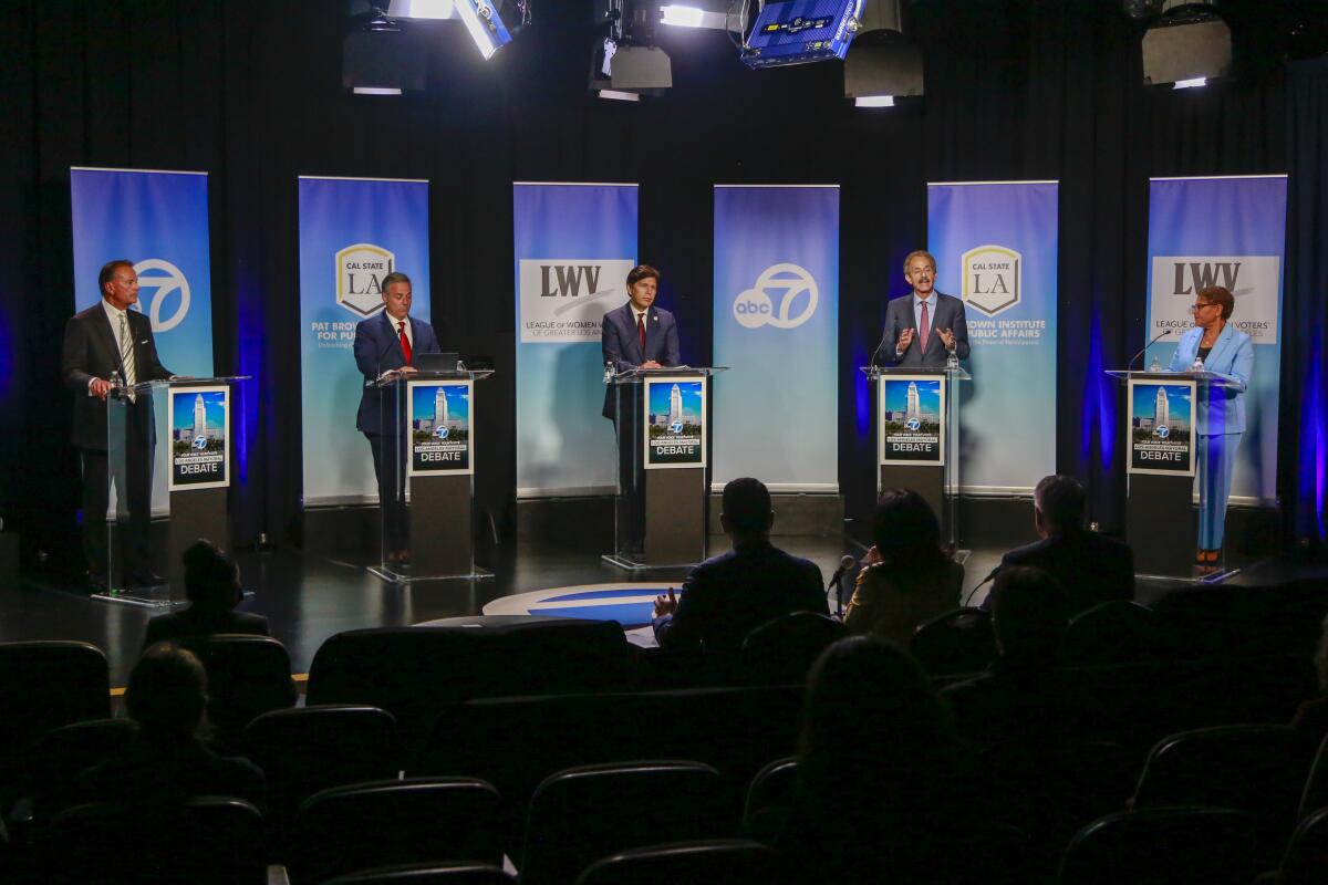 Rick Caruso, left, and Karen Bass, right, at a primary debate with other candidates