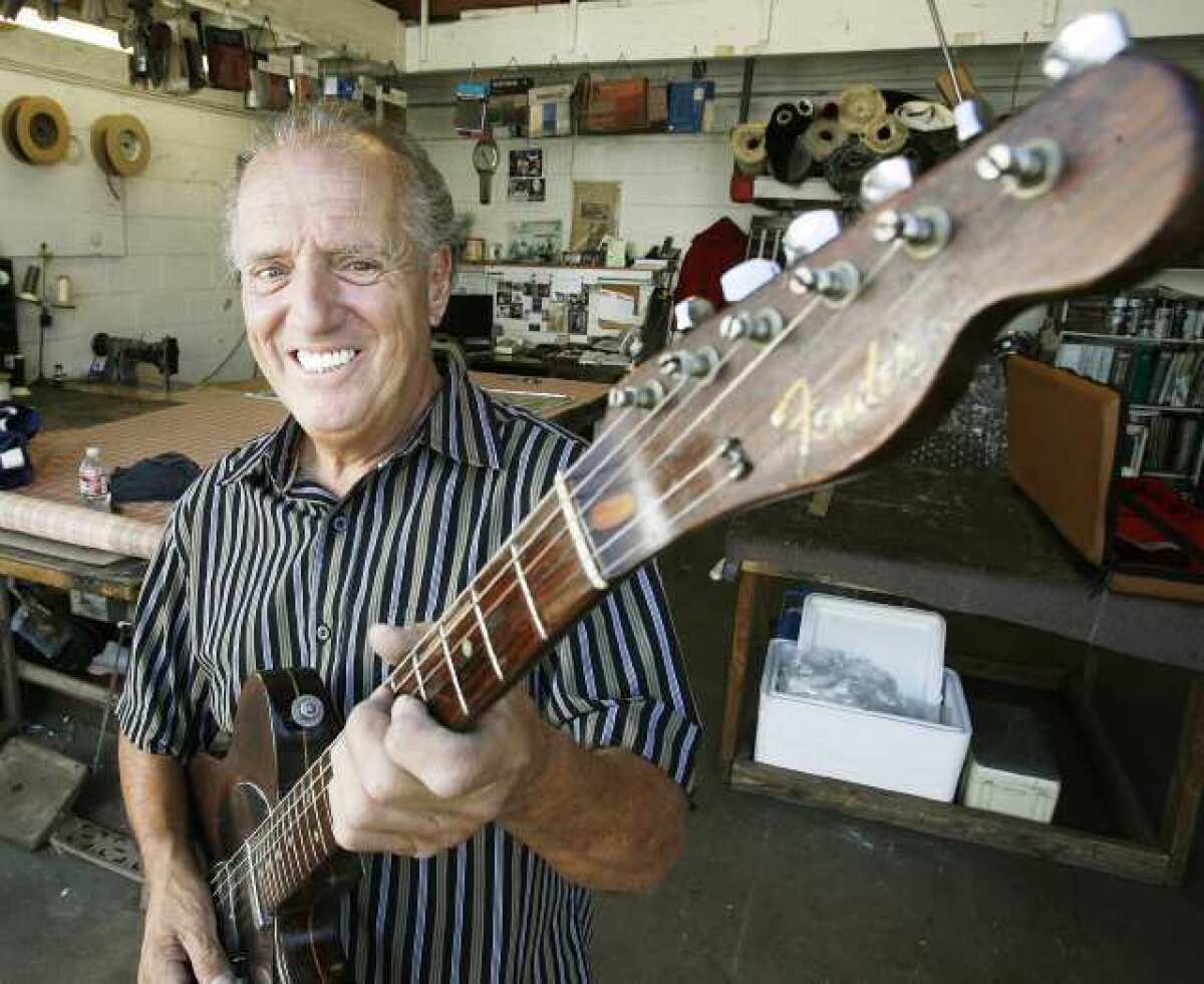 Carmine Sardo, holding his Fender guitar, stands at the front of his upholstery business. Sardo and his band Carmine Sardo and the Shuffle Brothers Band perform Sundays at Glendale's Big Fish.