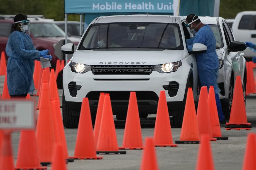 Healthcare workers administer nasal swabs to drivers and passengers at a drive-through COVID-19 testing site at Zoo Miami, Monday, Jan. 3, 2022, in Miami. (AP Photo/Rebecca Blackwell)