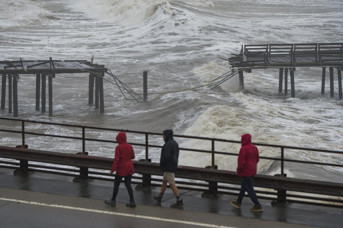 People walk along Cliff Drive to view the Capitola Wharf damaged by heavy storm waves