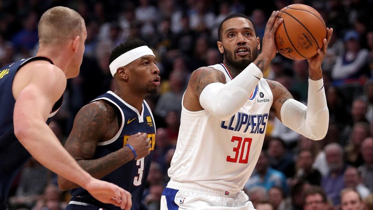 Mike Scott (30) of the Clippers puts up a shot against Torrey Craig (3) and Mason Plumlee (24) of the Denver Nuggets in the first quarter at the Pepsi Center on January 10, 2019 in Denver.