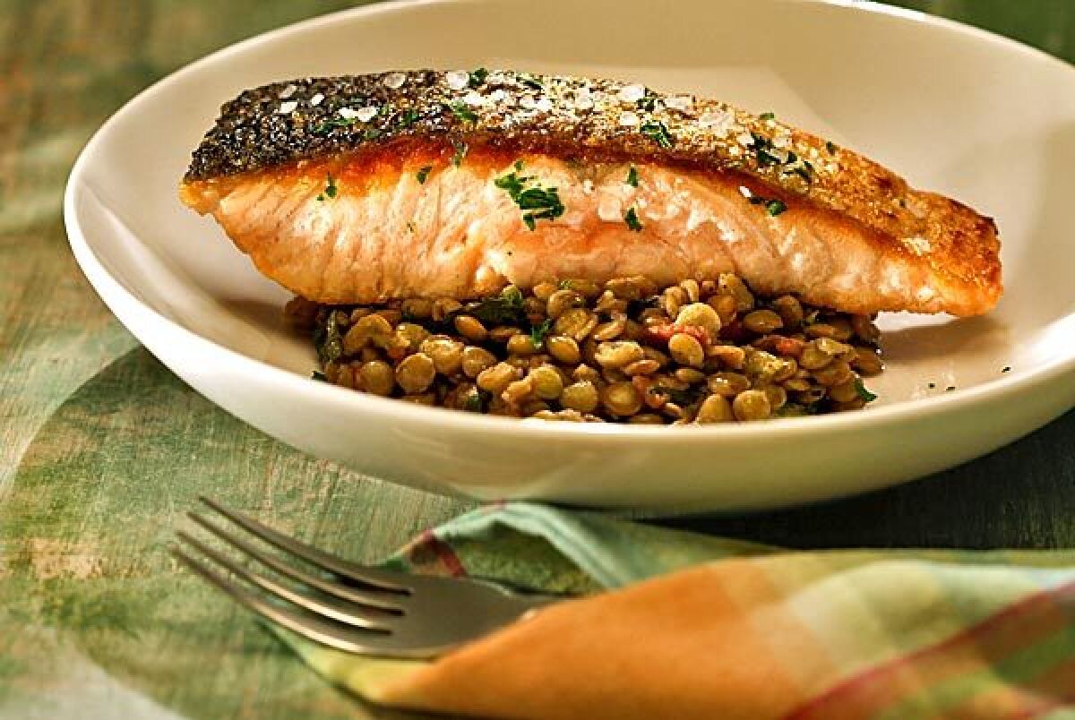 Crisp-skinned salmon on a bed of bacon-flavored lentils and dandelion greens. Recipe