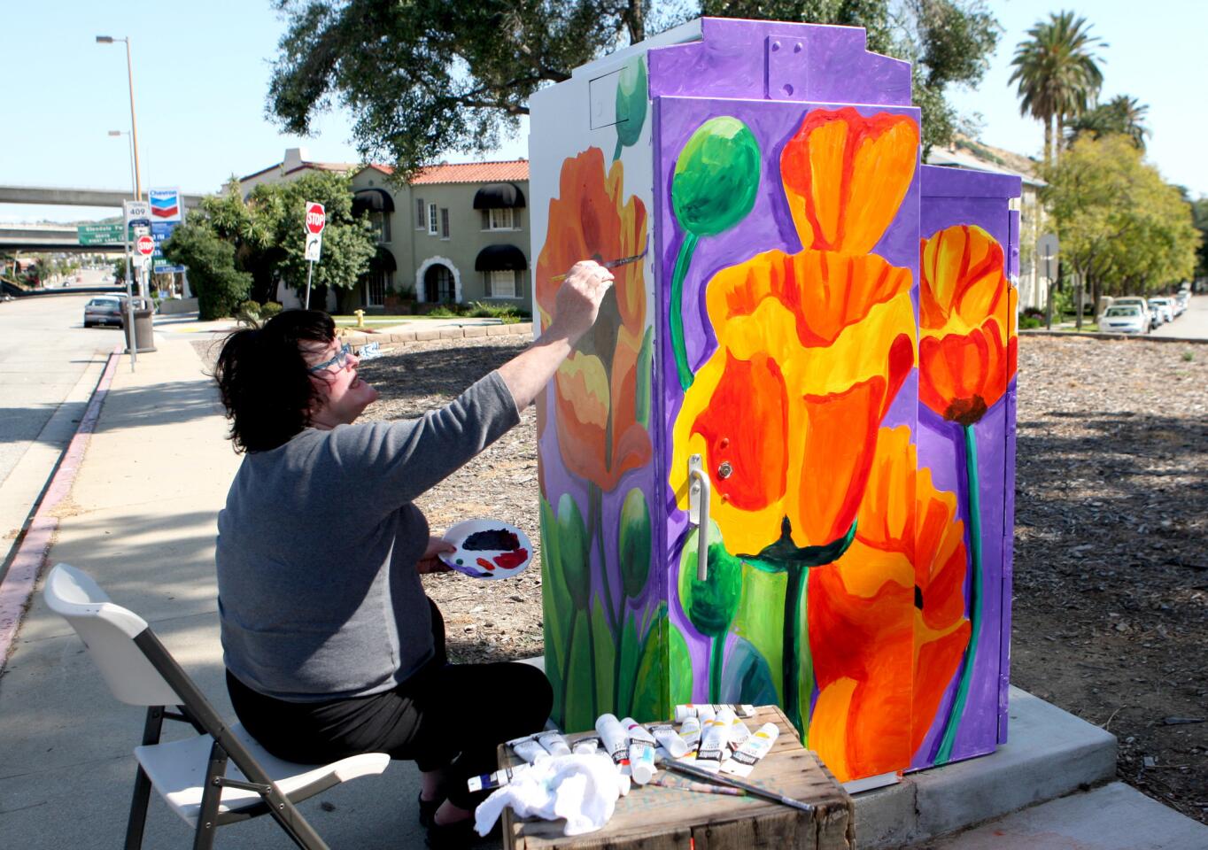 Holly Cleeland of Burbank paints poppy flowers on a utility box at Harvey Drive and Wilson Avenue in Glendale on Saturday, April 8, 2017.