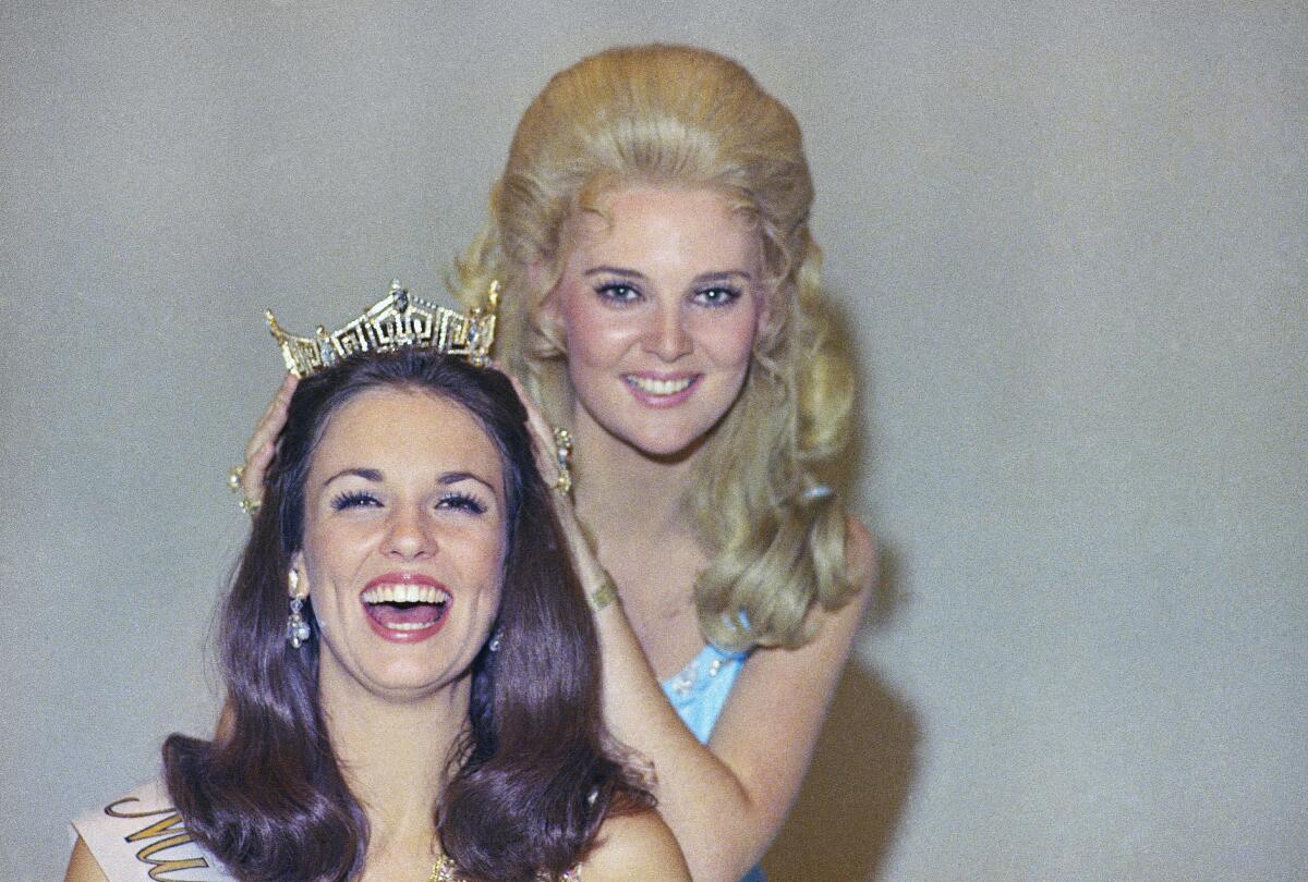 Miss America 1970 places a crown on her successor.