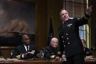 Lance Reddick, left, and Kiefer Sutherland, standing, in the movie "The Caine Mutiny Court-Martial."