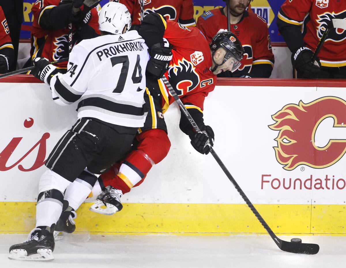 The Kings' Nikolai Prokhorkin hits the Flames' Mark Giordano into the boards during the second period Saturday night. 