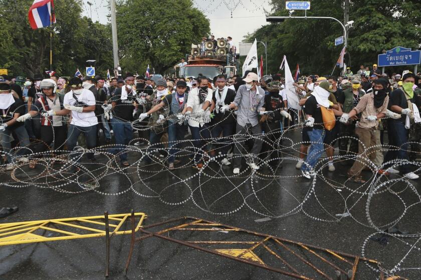 Anti-government protesters try to remove barbed wire set up by riot police during a rally in Bangkok, Thailand.