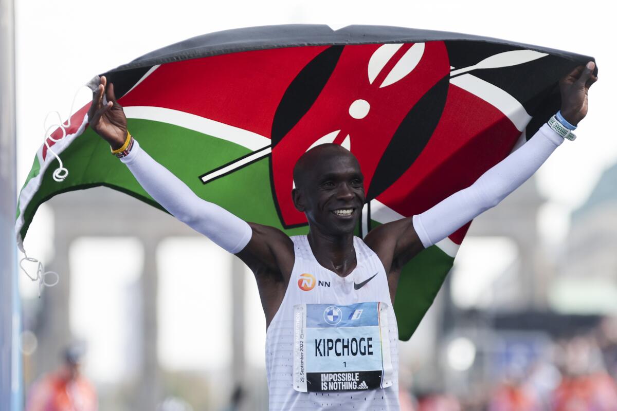 Kenya's Eliud Kipchoge waves his country's flag and celebrates after winning the Berlin Marathon on Sept. 25, 2022
