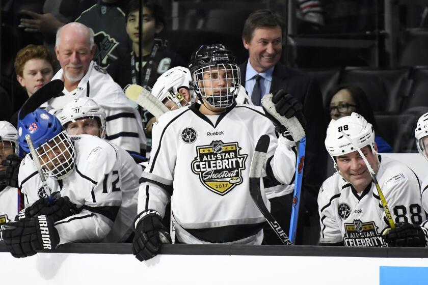Celebrity players, from left, Cuba Gooding Jr., Justin Bieber and Eric Lindros sit on the bench as Team Gretzky head coach Wayne Gretzky, top center, stands in the background during the first period on Jan. 28.