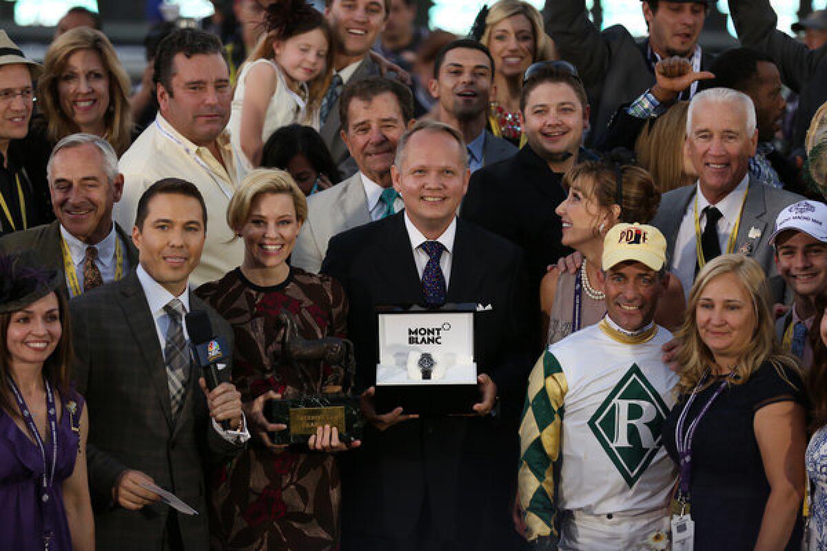 Elizabeth Banks and President and CEO of Montblanc North America, Jan-Patrick Schmitz, center, take part in the Breeders' Cup ceremonies.