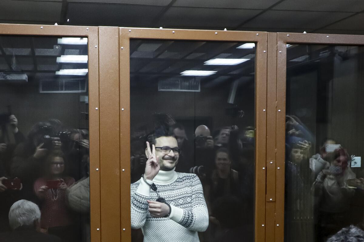El opositor ruso, Ilya Yashin, hace un gesto mientras está de pie dentro de un cubículo de vidrio 