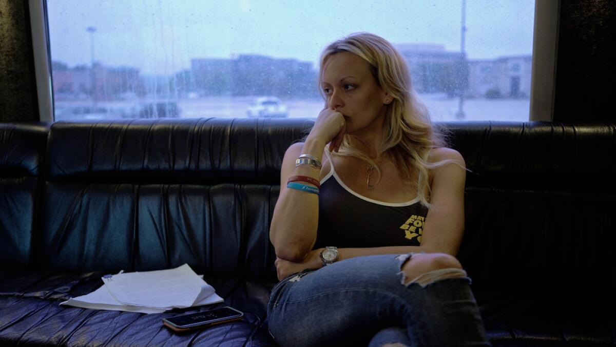 Stormy Daniels in a tank top sits inside her tour bus.