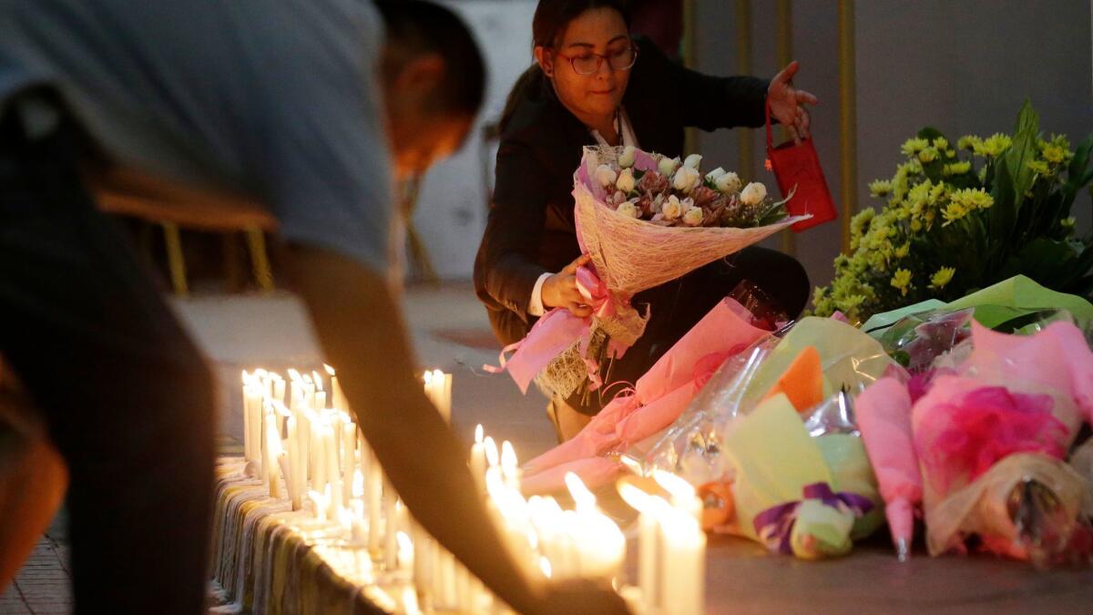 Mourners offer candles and flowers for victims of an attack at the Resorts World Manila complex.