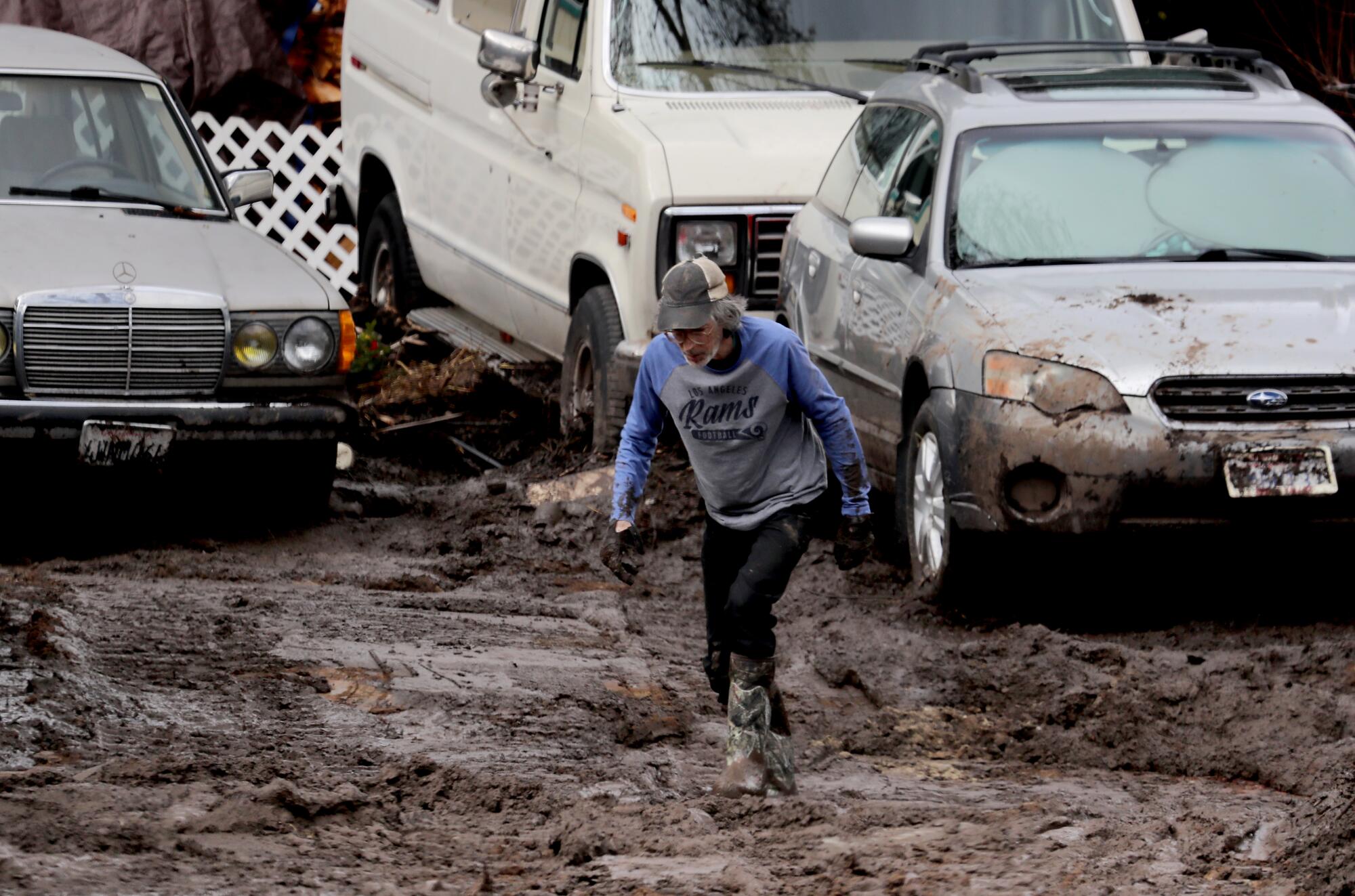 A person walks through mud near cars