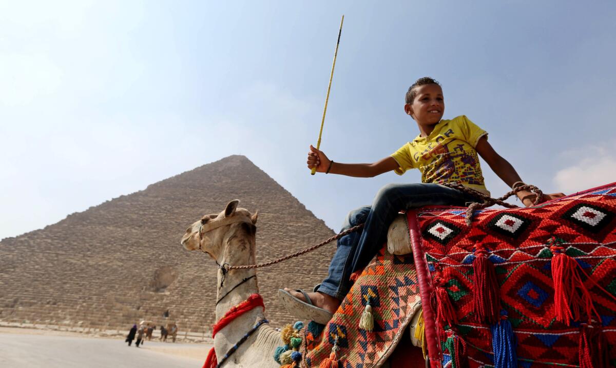 A young boy on a camel waits for tourists in front of the Great Pyramid of Khufu, the largest of the pyramids at the historical site of Giza, near the Egyptian capital, Cairo.