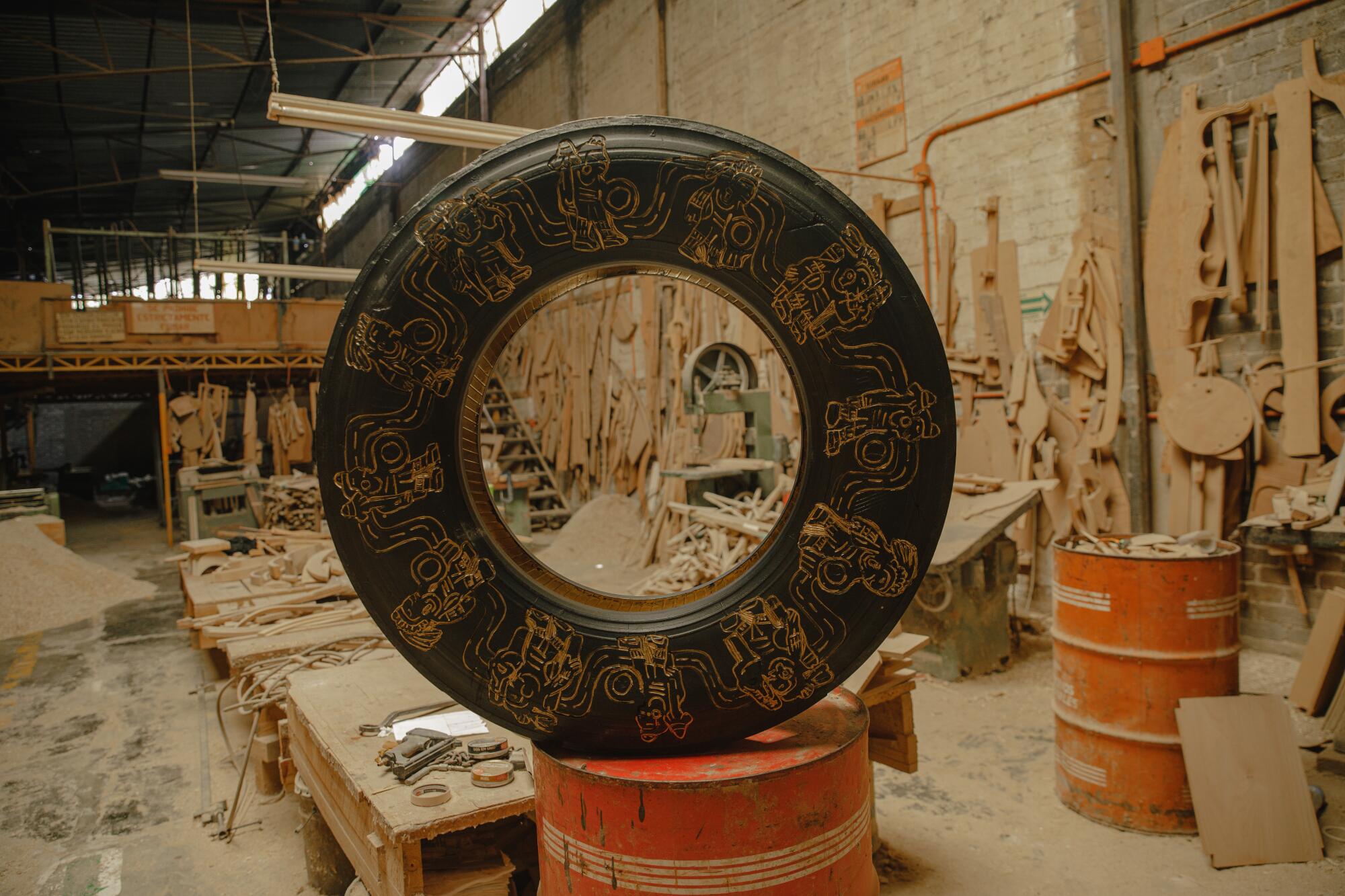 The side of a tire sculpture has been carved with designs reminiscent of ancient hieroglyphs.