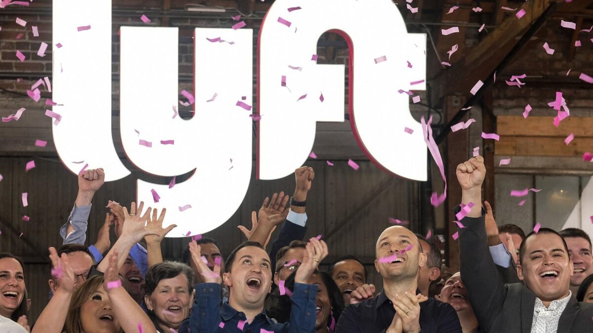 Lyft co-founders John Zimmer, front second from left, and Logan Green, front second from right, cheer as they ring a ceremonial opening bell in Los Angeles on March 29.