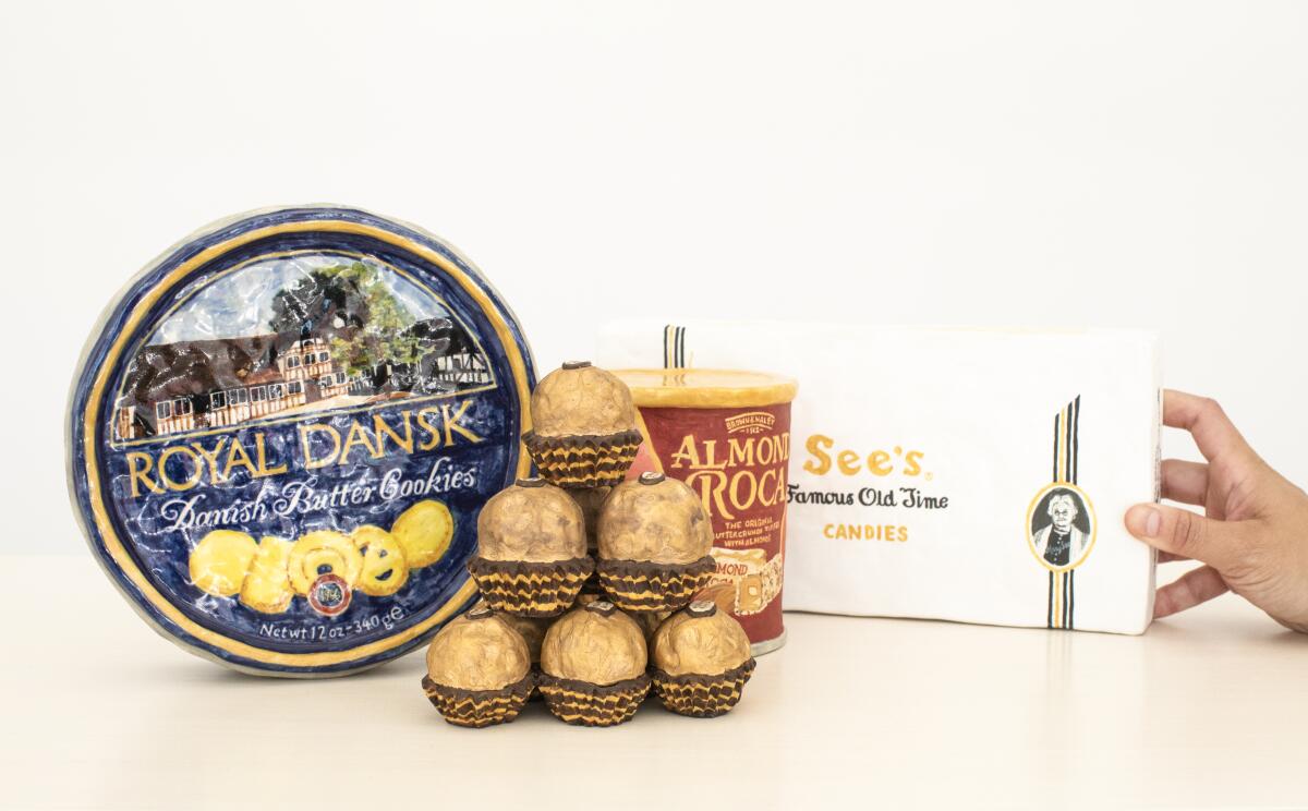 Ceramic artworks shaped like a tin of Royal Dansk cookies, Ferrero Rocher chocolates, Almond Roca and a box of See's candy.