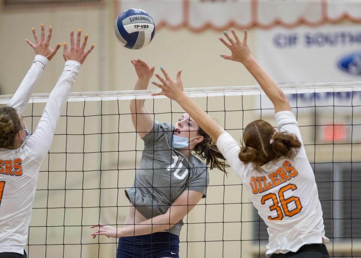 Newport Harbor's Anne O'Brien hits into Huntington Beach's Haylee LaFontaine, left, and Kylie Leopard.