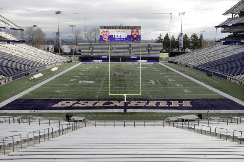 Photos of Washington head coach Chris Petersen, left, and defensive coordinator Jimmy Lake are shown on the scoreboard at Husky Stadium after an announcement that Petersen is leaving his position and that Lake is assuming it, Tuesday, Dec. 3, 2019, in Seattle. Petersen unexpectedly resigned at Washington on Monday, a shocking announcement with the Huskies coming off a 7-5 regular season and bound for a sixth straight bowl game under his leadership. Petersen will coach Washington in a bowl game, his final game in charge. (AP Photo/Elaine Thompson)
