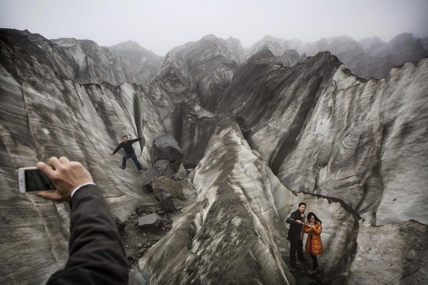 Chinese tourist s pose for pictures in the tongue of Glacier 1 at the base of the 24,790 ft Mount Gongga, known in Tibetan as Minya Konka in Hailuogou, Garze Tibetan Autonomous Prefecture.