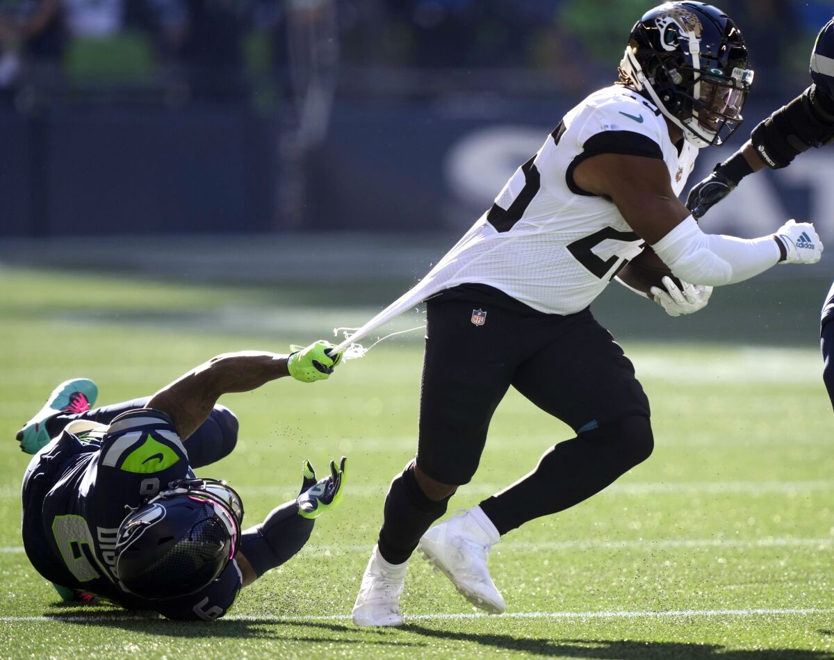Jacksonville Jaguars running back James Robinson, right, is grabbed by his jersey by Seattle Seahawks free safety Quandre Diggs during the first half of an NFL football game, Sunday, Oct. 31, 2021, in Seattle. (AP Photo/Stephen Brashear)