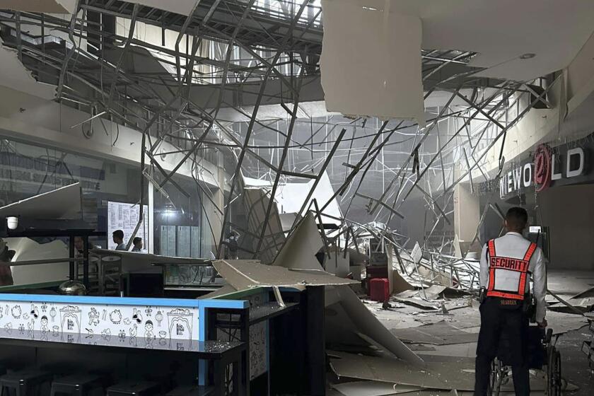 Un guardia de seguridad camina cerca del techo caído de un centro comercial tras un sismo en General Santos City, en el sur de Filipinas, el viernes 17 de noviembre de 2023. (AP Foto/Shaira Ann Sandigan)