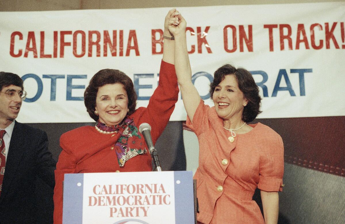 two women hold their hands up in front of a sign that reads "get california back on track"