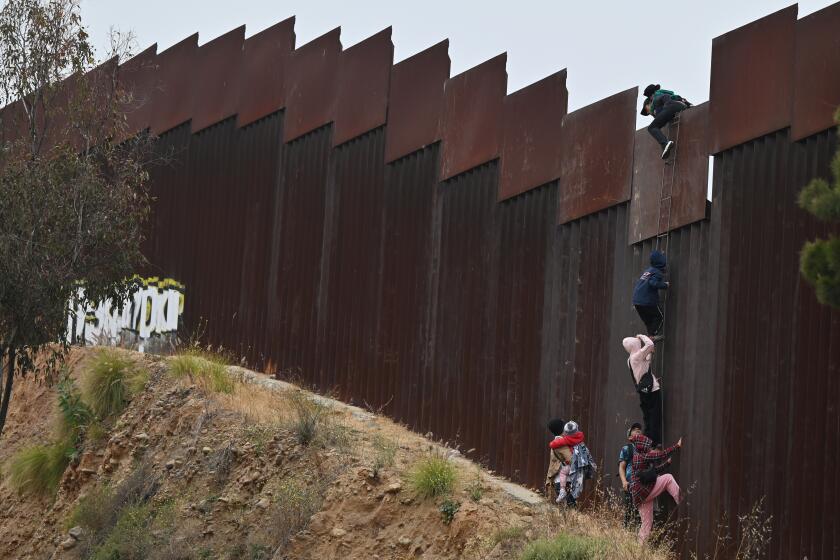 A group of adult and child migrants are smuggled at the Tijuana-San Diego border, as they climb the wall to seek asylum to the United States in Tijuana, Mexico, on Friday, June 7, 2024. The president of Mexico, Andres Manuel Lopez Obrador, said recently that he was seeking an agreement with President Joe Biden, where migrants deported following the new executive order signed by Biden would be sent directly to their country of origin, instead of being transferred to Mexico during a conference. (Carlos Moreno / The San Diego Union-Tribune)