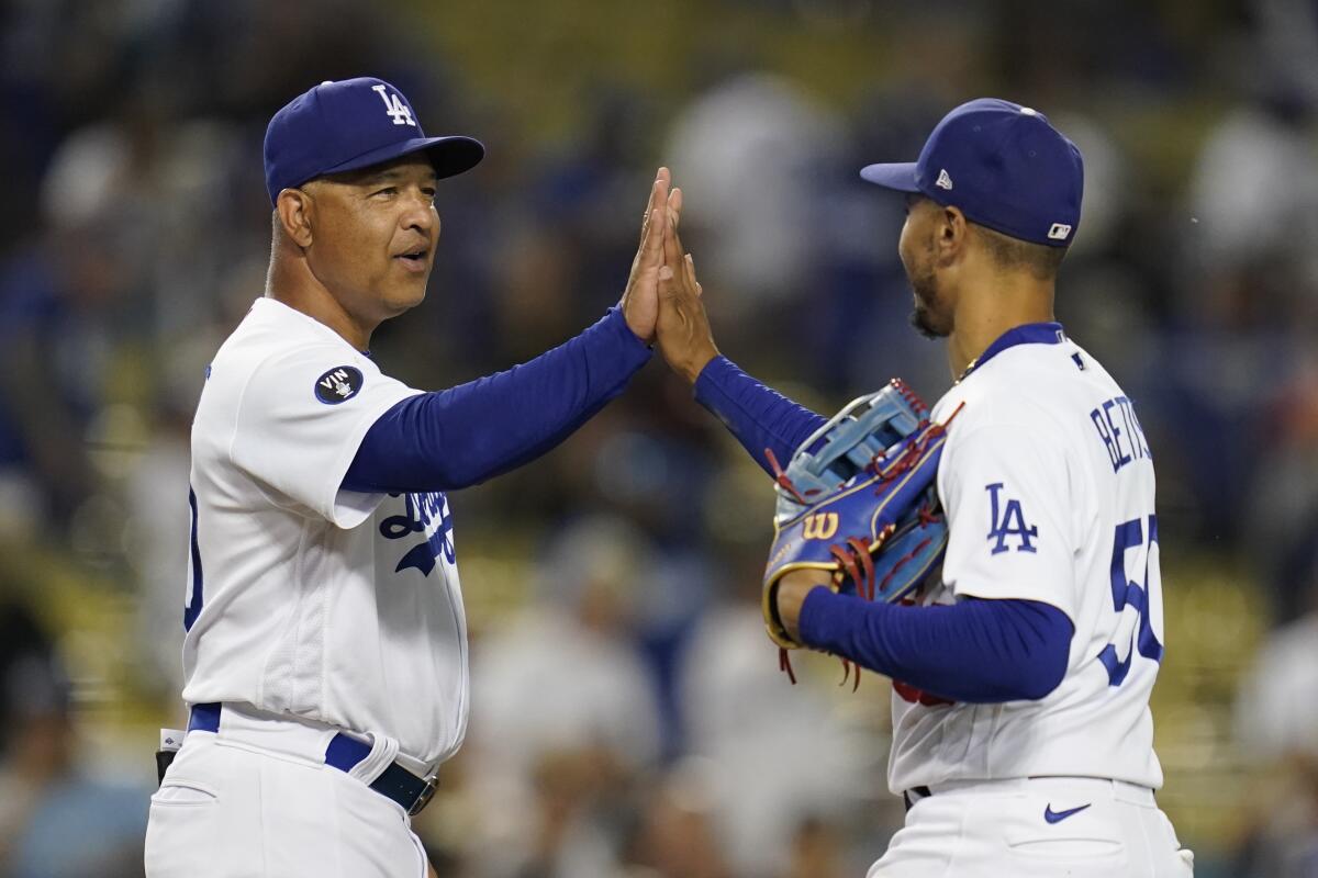 Dodgers manager Dave Roberts, left, high-fives right fielder Mookie Betts after a 12-6 win over the Milwaukee Brewers.