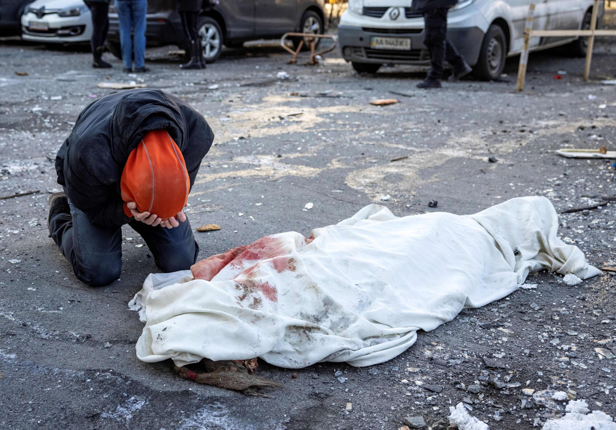 A person mourns next to a wrapped body near a residential building which was hit by the debris 