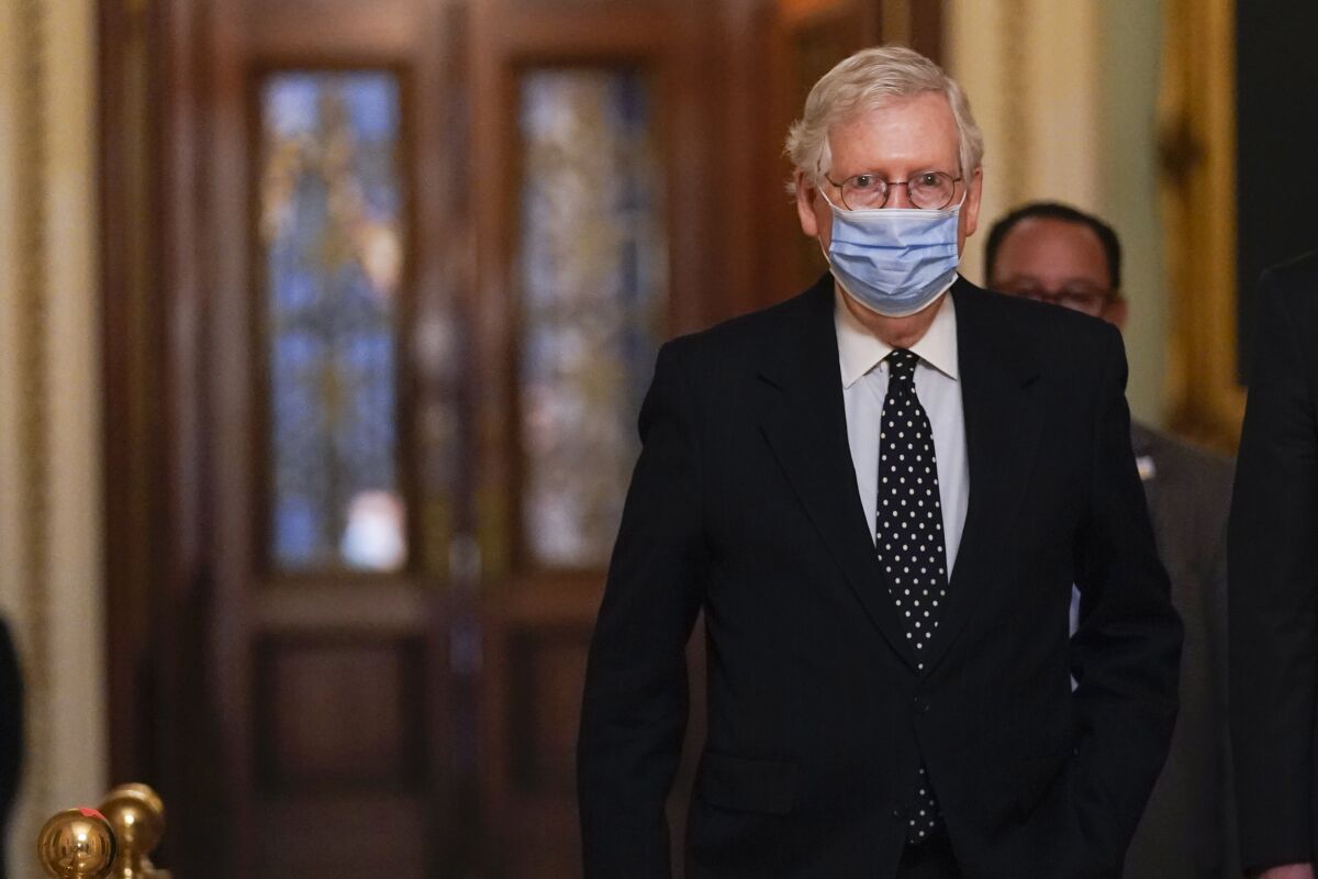 Mitch McConnell, wearing a blue mask, walks through Capitol halls