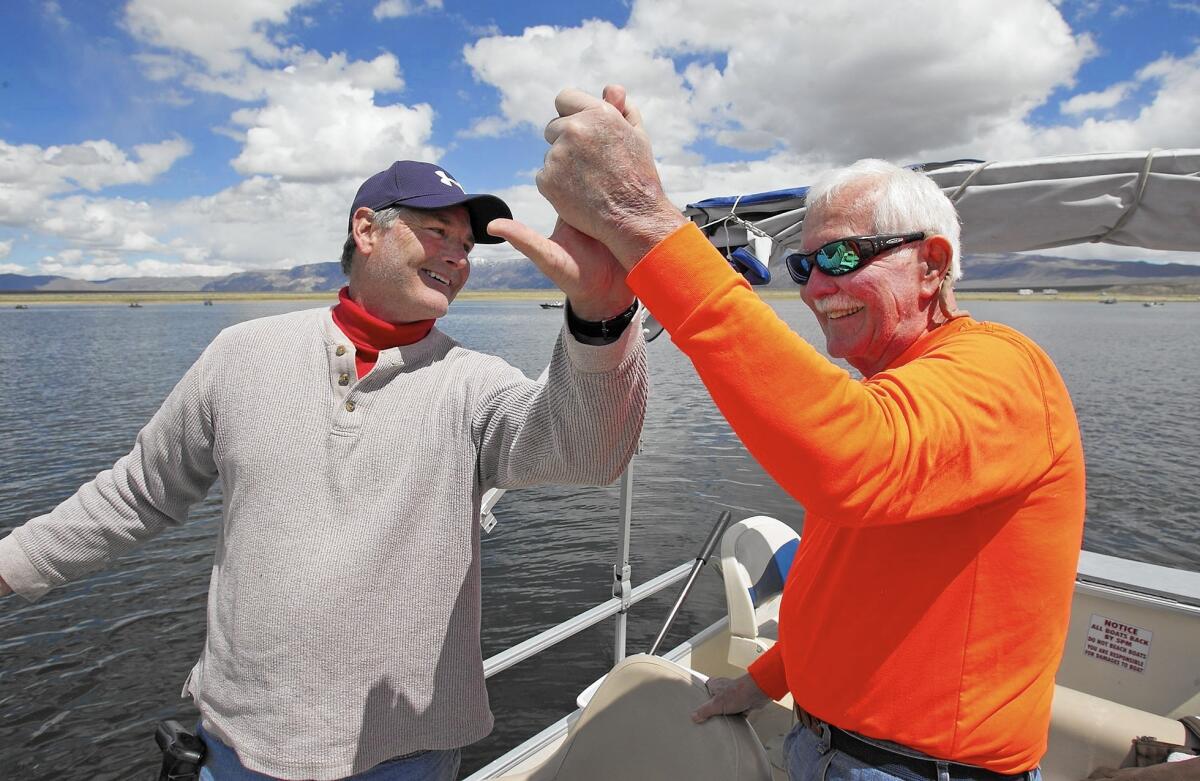 Mark, left, and Dick Hoagland high-five after bringing a fish onboard during their annual fishing trip to Crowley Lake, near Mammoth Lakes.