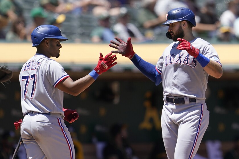 Texas Rangers' Joey Gallo, right, is congratulated by Andy Ibanez, left, after hitting a two-run home run during the fifth inning of a baseball game against the Oakland Athletics in Oakland, Calif., Thursday, July 1, 2021. (AP Photo/Jeff Chiu)