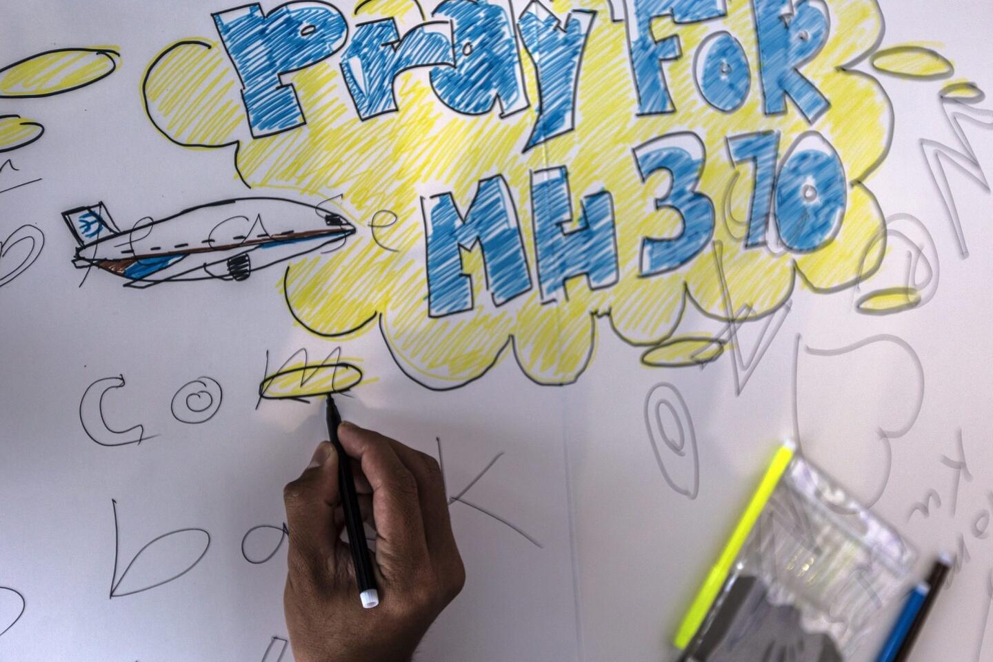 A visitor draws a message for the missing Malaysian Airlines plane on the wall of hope at Kuala Lumpur International Airport, Sepang, Selangor, Malaysia 19 March 2014.