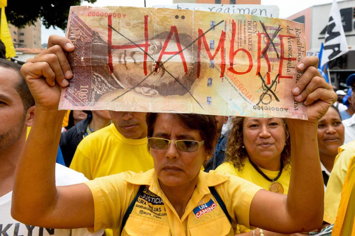 A woman holds a sign reading "Hunger" during a demonstration against the government of Venezuelan President Nicolas Maduro in Caracas on May 14, 2016.