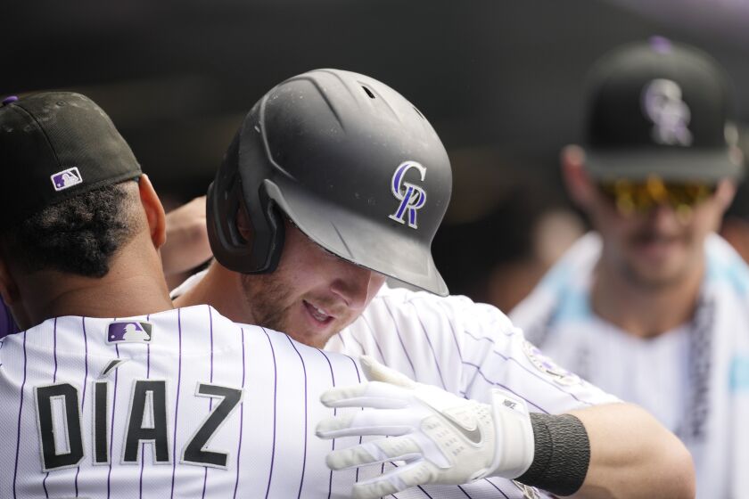 Colorado Rockies' Elias Diaz, leftt, hugs Ryan McMahon who returns to the dugout after hitting a two-run home run off New York Mets relief pitcher Stephen Nogosek in the fifth inning of a baseball game Sunday, May 28, 2023, in Denver. (AP Photo/David Zalubowski)
