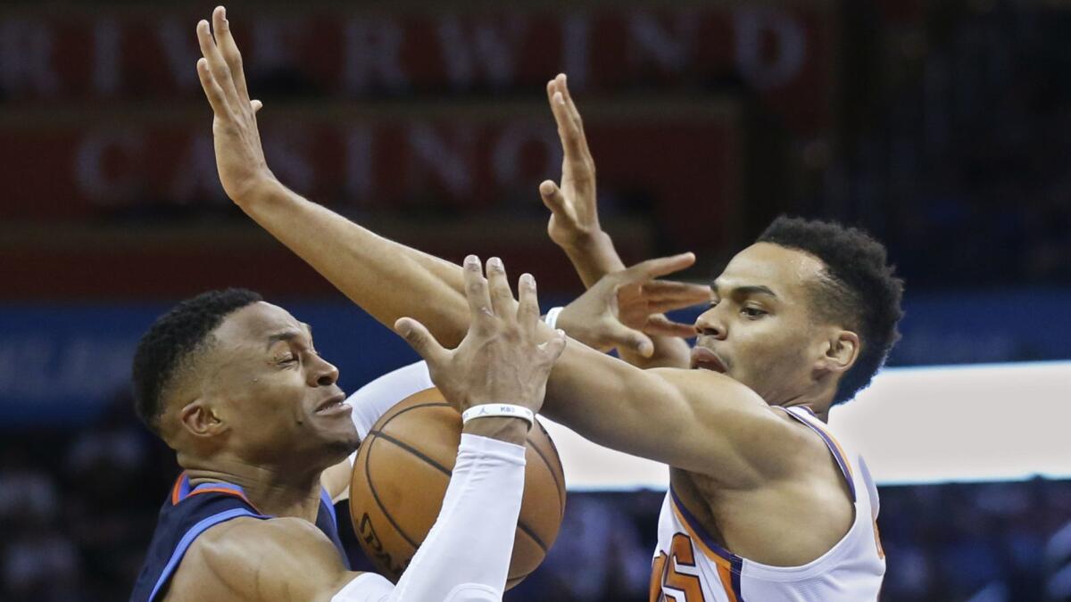 Oklahoma City's Russell Westbrook, left, loses control of the ball after a foul by Phoenix's Elie Okobo.