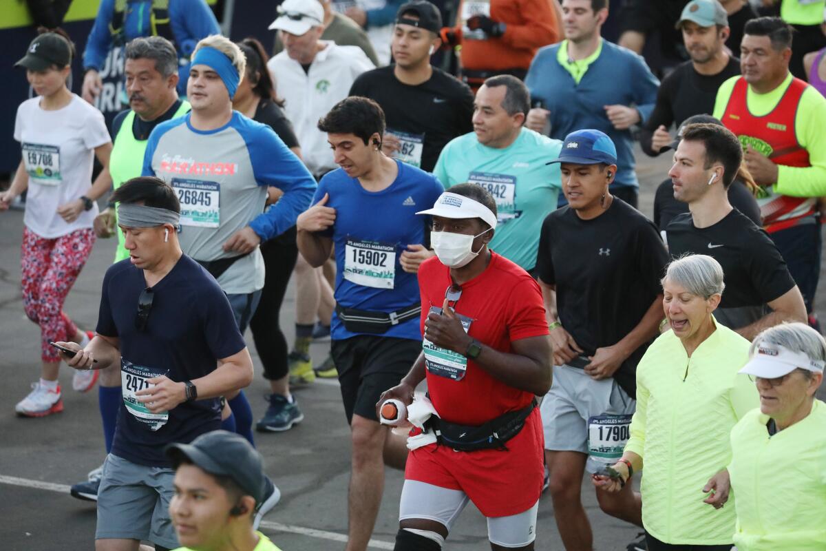 A masked runner is among the thousands beginning the Los Angeles Marathon on March 8, 2020.