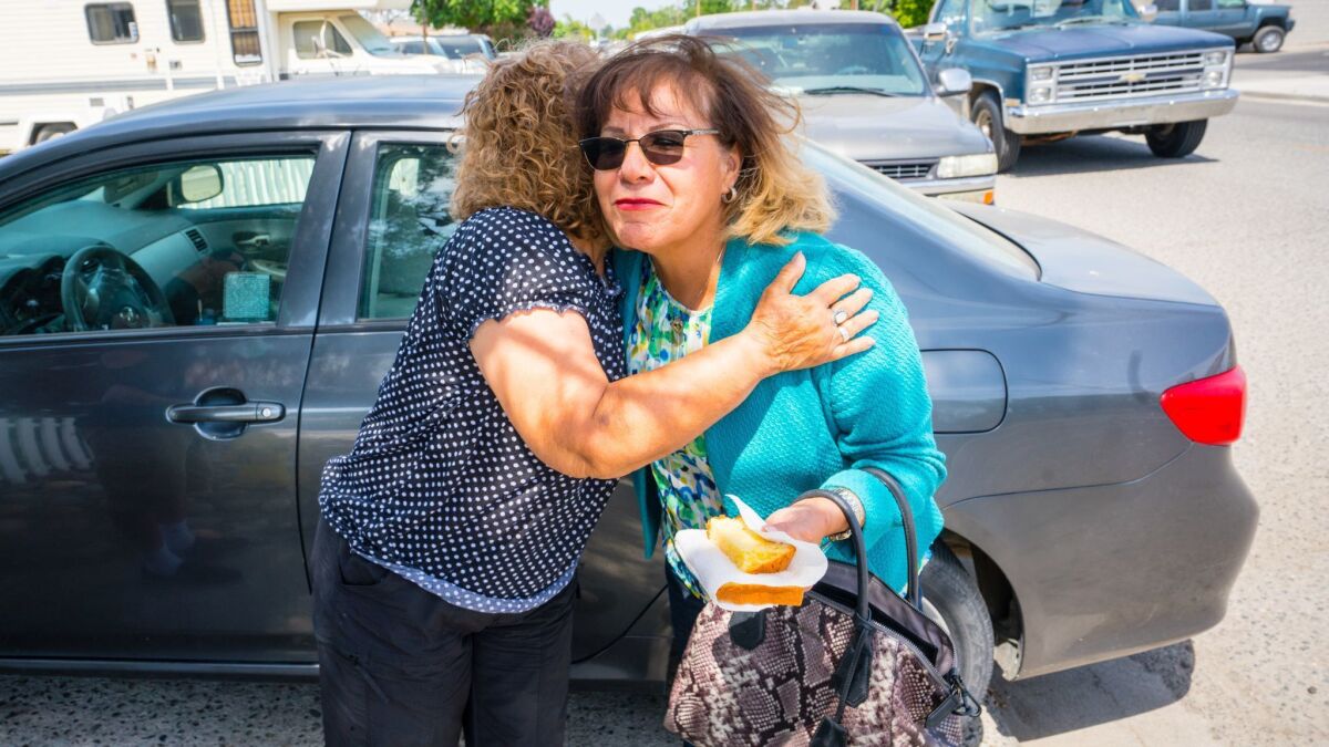 Mary Gonzales-Gomez, left, hugs Carmen Montano before passing out Democratic voter guides in Corcoran, Calif.