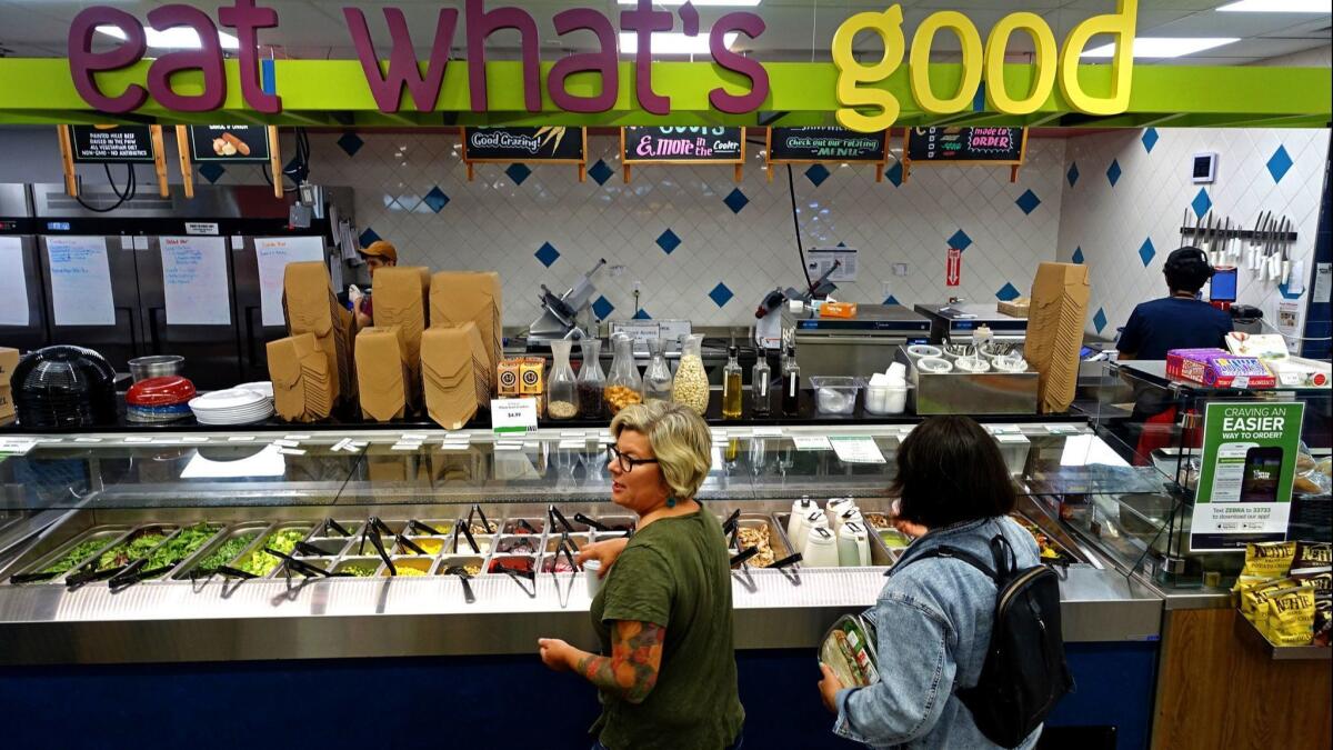 Lisa Sedlar tidies up the salad bar at a Green Zebra Grocery.