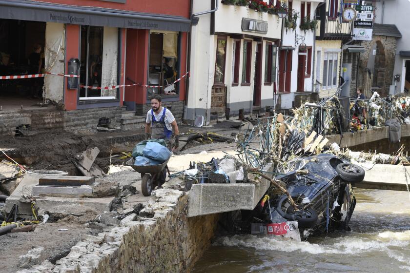 A man helps with the cleanup by carrying rubbish and debris after heavy rain and flooding along the Erft in Bad Münstereifel, Germany, Saturday, July 17, 2021. On the night of July 15, the Erft floods totally devastated the historic core of the city and flooded streets and shops. Gas, electricity and telephone lines were dangerously exposed. (Roberto Pfeil/dpa via AP)