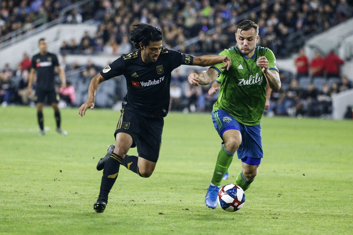 Los Angeles FC forward Carlos Vela, left, vies against Seattle Sounders forward Jordan Morris during the second half of the MLS soccer Western Conference final Tuesday, Oct. 29, 2019, in Los Angeles. The Sounders won 3-1. (AP Photo/Ringo H.W. Chiu)