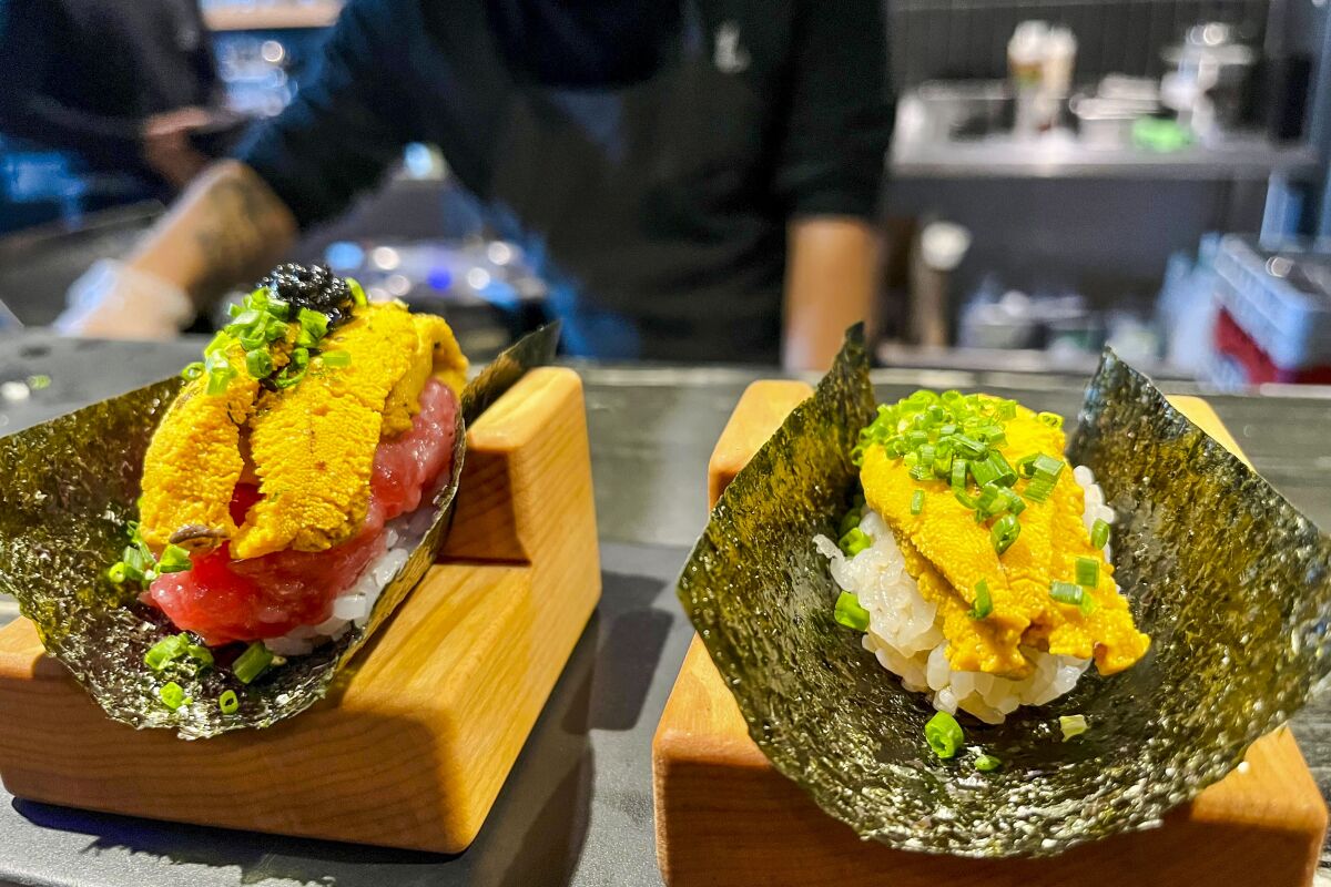 The uni and toro and uni hand rolls are placed atop pieces of warm seaweed in wooden holders.